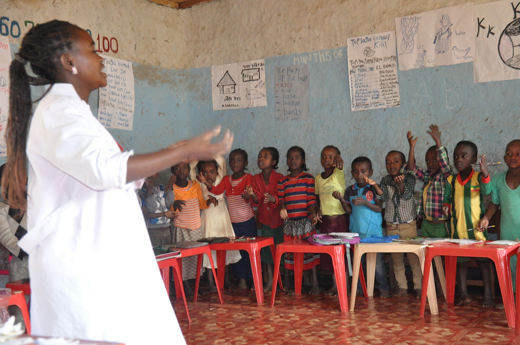 Opettaja ja alakouluikäisiä lapsia äidinkielisen opetuksen luokassa etiopialaisessa koulussa.
