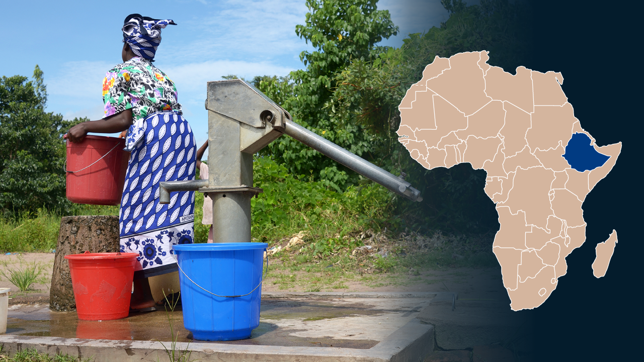 An Ethiopian woman lifting a bucket of water at a waterpoint.